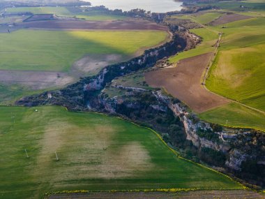Gravina nehrinin geçitleri, kayaların üzerine oyulmuş kanyonlar ve ekili tarlalar.
