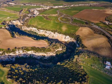 Gravina nehrinin geçitleri, kayaların üzerine oyulmuş kanyonlar ve ekili tarlalar.