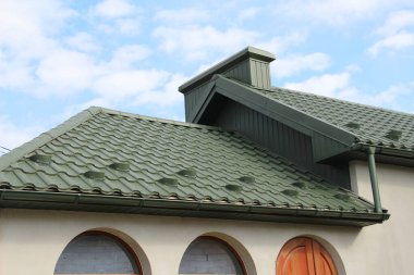 Çatısı metal kiremitlerle kaplı olan ev.