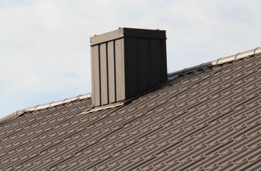 Metal kiremitlerle ya da metal profiliyle kaplı bir evin çatısındaki baca.