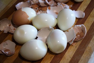 On the kitchen board, hard-boiled chicken eggs are peeled clipart