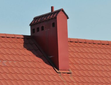 Metal kiremitlerle ya da metal profiliyle kaplı bir evin çatısındaki baca.