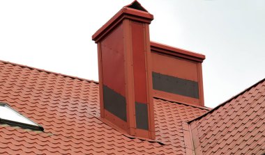 Metal kiremitlerle ya da metal profiliyle kaplı bir evin çatısındaki baca.