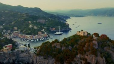 Dağlık ve ağaçlarla dolu kıyıları ve teknelerle dolu deniz tarafından kucaklanmış muhteşem evleri olan kusursuz bir manzara. 4K