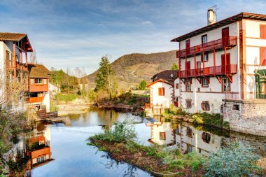 Saint-Jean-Pied-de-Port, Fransa - 24 Aralık 2022: Nive Nehri 'nin Saint Jean Pied de Port köyünden geçişi ve arka planda Pireneler. Fransa.
