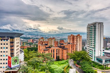 Medellin, Kolombiya - Mayıs 2019: Bulutlu havada dağların arasında şehrin havadan görünüşü