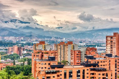 Medellin, Kolombiya - Mayıs 2019: Bulutlu havada dağların arasında şehrin havadan görünüşü