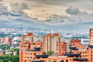 Medellin, Kolombiya - Mayıs 2019: Bulutlu havada dağların arasında şehrin havadan görünüşü