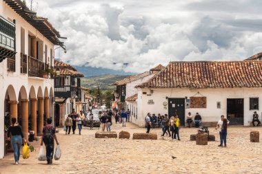 Villa de Leyva, Kolombiya - 20 Nisan 2019: Bulutlu bir günde tarihi kent meydanında kalan turistler. 