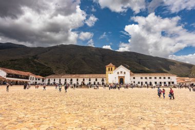 Villa de Leyva, Kolombiya - 20 Nisan 2019: Bulutlu bir günde tarihi kent meydanında kalan turistler. 
