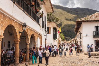 Villa de Leyva, Kolombiya - 20 Nisan 2019: Bulutlu bir günde tarihi kent meydanında kalan turistler. 