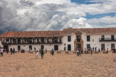 Villa de Leyva, Kolombiya - 20 Nisan 2019: Bulutlu bir günde tarihi kent meydanında kalan turistler. 
