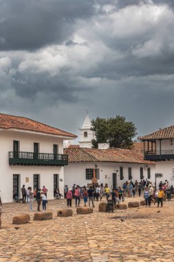 Villa de Leyva, Kolombiya - 20 Nisan 2019: Bulutlu bir günde tarihi kent meydanında kalan turistler. 