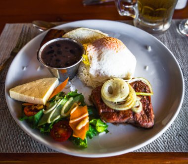 Beyaz tabakta sebzeli biftek manzarası.