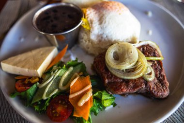 Beyaz tabakta sebzeli biftek manzarası.