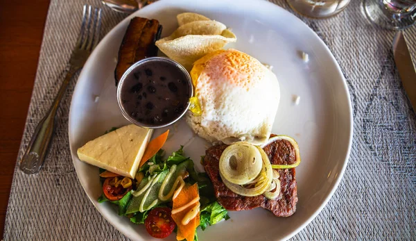 Beyaz tabakta sebzeli biftek manzarası.