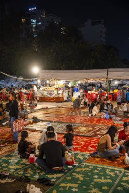 Phnom Penh, Cambodia - January 26 2025 : People eating food outdoor while sitting on the carpets 