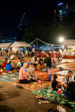 Phnom Penh, Cambodia - January 26 2025 : People eating food outdoor while sitting on the carpets 