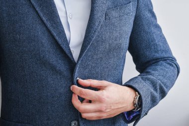 Business man fastens a button on blue tweed blazer with white shirt.