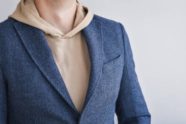 Close up detail of men outfit, blue tweed blazer combined with light beige hoodie. Selective focus.