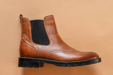 Light tan chelsea men boots on light beige background. Copy space.