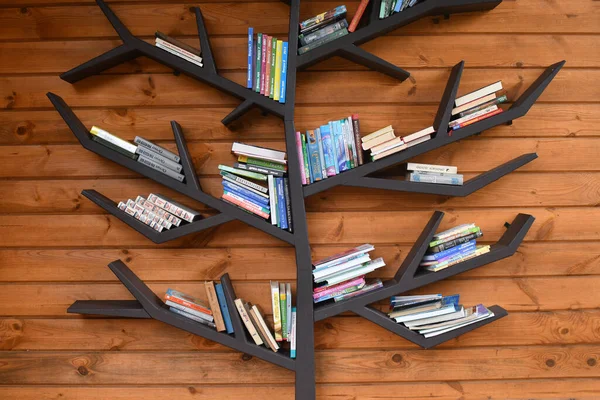 多くの本を持つ創造的な木の形の本の棚 素朴な木製の壁の背景に — ストック写真