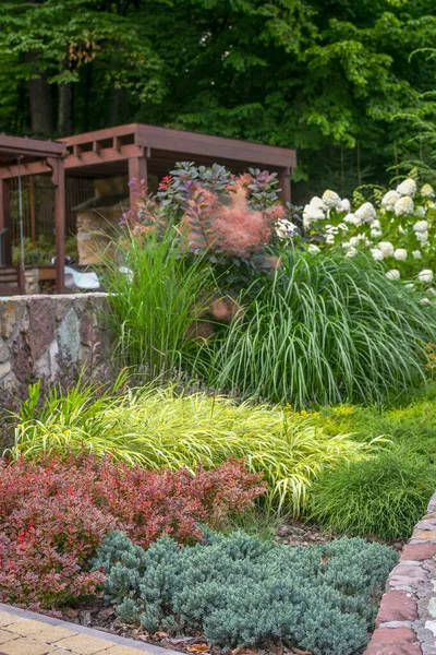 装飾的な緑の植物 茂みや花の多くと庭の断片は 背景に木製のガゼボで 選択的焦点 — ストック写真