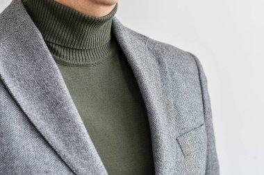 Erkeklerin üstünlüğü, şık erkeklerin yeşil süveteri ve gri tüvit ceket. Seçici odak.