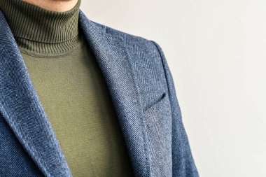 Erkeklerin üstündekileri yakın çekim, koyu gri tüvit ceket ve yeşil kazak. Seçici odak.