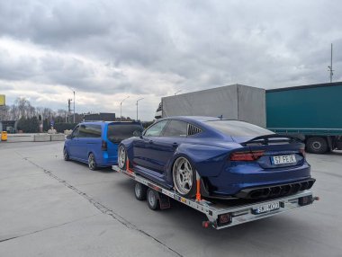 Bulutlu gökyüzünün altındaki benzin istasyonundaki römorkta AUDI A7 spor arabası ayarlandı
