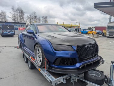 Bulutlu gökyüzünün altındaki benzin istasyonundaki römorkta AUDI A7 spor arabası ayarlandı