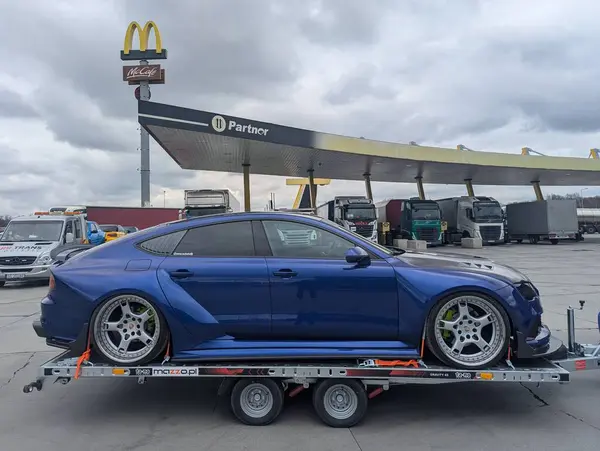 Bulutlu gökyüzünün altındaki benzin istasyonundaki römorkta AUDI A7 spor arabası ayarlandı