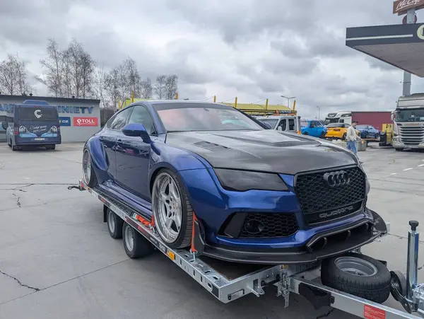 Bulutlu gökyüzünün altındaki benzin istasyonundaki römorkta AUDI A7 spor arabası ayarlandı