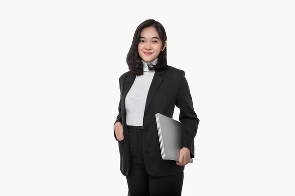 アジアの若い女性従業員は黒のスーツを着ており ジェスチャーはラップトップを側面と前面にしっかりと白い背景に向けて保持しています ビジネス女性は立ちながらコンピュータを使う — ストック写真