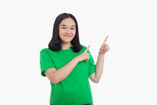 Neşeli heyecanlı Asyalı kadın, yeşil tişört giyen ve izole edilmiş beyaz arka planda duran boş fotokopi aletiyle sol tarafı işaret ediyor.