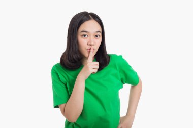 Genç Asyalı kadın sessiz ve sessiz olmak istiyor. Parmakları dudaklarında ve gizli bir konseptle.