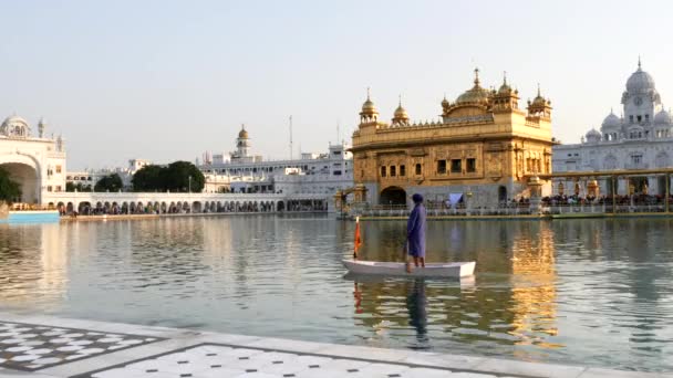 警備員がインドのアムリトサルの黄金寺院のプールの周りにボートを漕いでいます — ストック動画