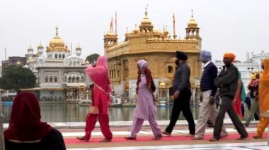 AMRITSAR, Hindistan - 18 Mart 2019: Hindistan 'ın Amritsar kentindeki altın tapınağın yanından geçen ziyaretçiler