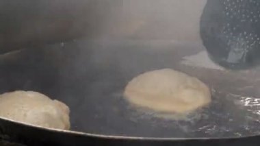 Poori ekmeği Amritsar, India 'da bir restoranda yağ içinde pişirilirken genişler... 4K 60p