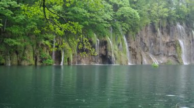Yağmurlu bir bahar gününde Hırvatistan 'daki Plitvice Gölleri' ndeki bir şelale ve gölün kenarında milli park