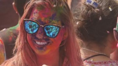 Ağır çekimde, mavi güneş gözlüğü takan, Hindistan, Jaipur 'da bir holi partisinde dans eden Amerikalı bir kadın turisti yakından çekiyoruz.