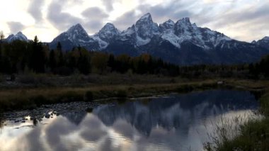 Güneş, sonbahar karıyla kaplı Teton dağlarının ardında Wyoming 'deki Grand Teton Ulusal Parkı' nda batıyor.