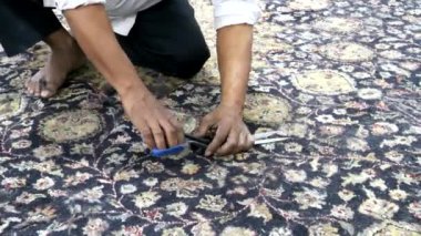 Hintli bir fabrika işçisi Hindistan 'da bir halıyı makasla buduyor.
