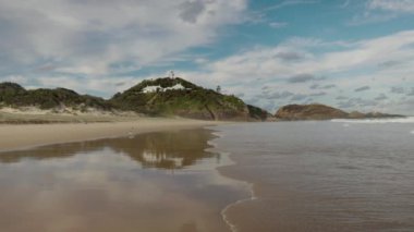 Sugarloaf Point deniz fenerinin kumsalında, Avustralya 'nın NSW kentindeki fok kayalıklarındaki bir dalganın yavaş çekim klipsi.