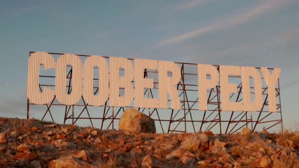南オーストラリアのアウトバックのクーバーペディーの丘の上のクーバーペイドという言葉で大きな金属サインでズーム — ストック動画