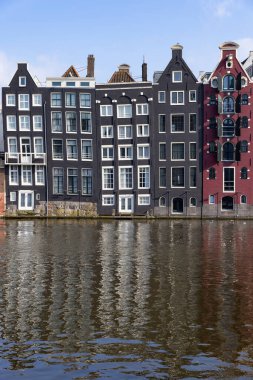 AMSTERDAM, NETHERLANDS-APRIL, 17, 2023: Amsterdam, Hollanda 'daki bir yolcu gemisinden Damrak Kanalı' ndaki ünlü dans eden evlerin yakın görüntüsü