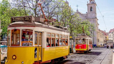 LISBON, PORTUGAL - APRIL, 27, 2023: iki tarihi tramvay yaklaşıyor ve Lizbon caddesinden geçiyor