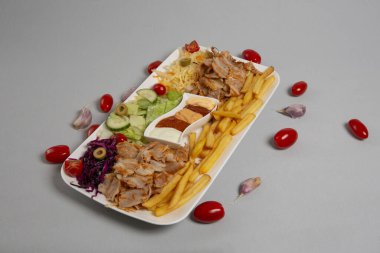 Beyaz arka planda humus, falafel ve sebze tabağı.