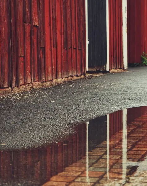 Лужа Дороге Рядом Красным Деревянным Зданием — стоковое фото