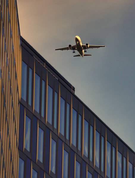 A plane flying over a modern building